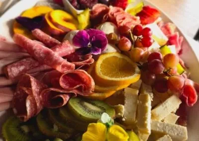 Close-up charcuterie board with meats, cheeses, fruits, and edible flowers.