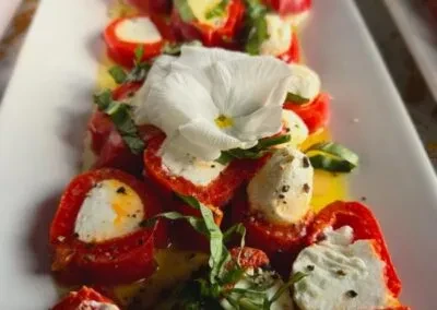 Cheese-stuffed red peppers or tomatoes with basil, olive oil, and a flower.