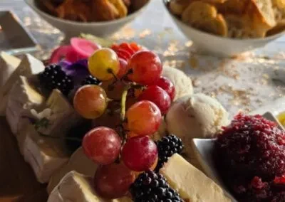 Close-up food platter with grapes, cheese, blackberries, compote, and creamy dip.