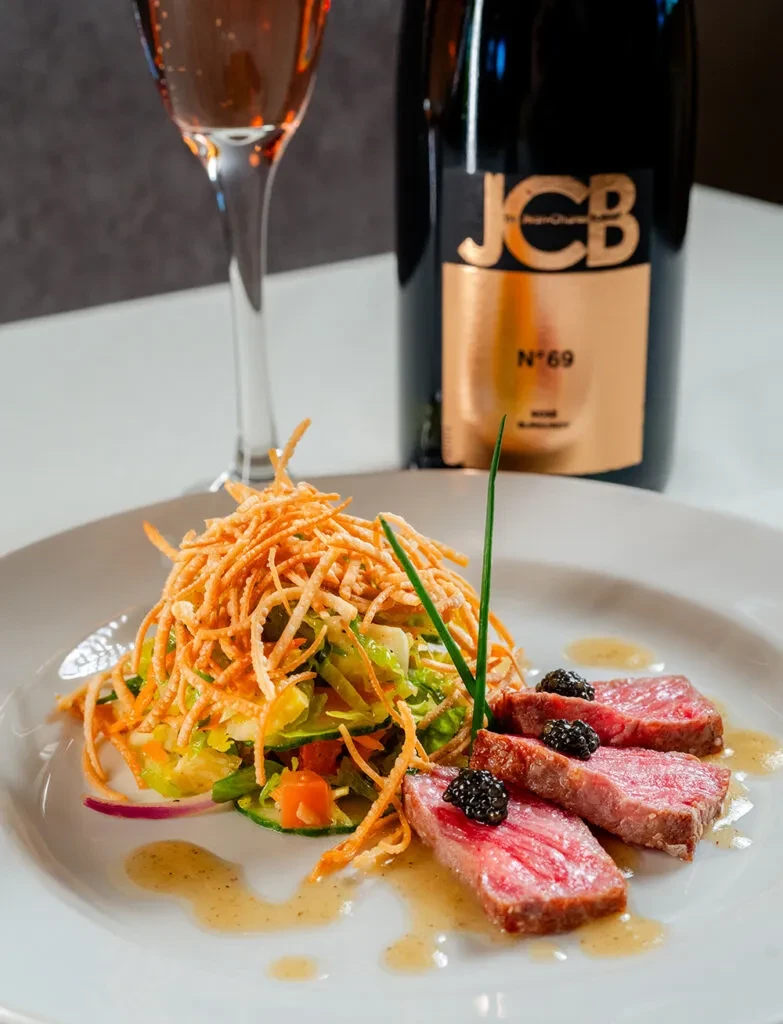 Gourmet rare meat, caviar, salad, and JCB N°69 rosé sparkling wine.