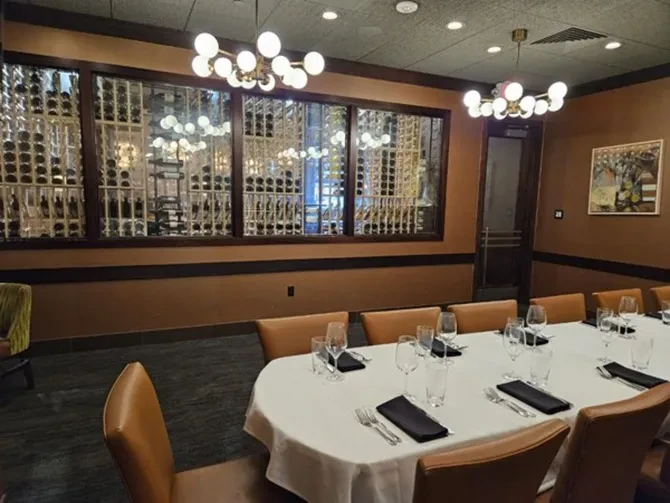 Upscale dining room with set table, leather chairs, and wine cellar.