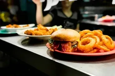 Close-up of a bacon burger, onion rings, and other fried dishes.
