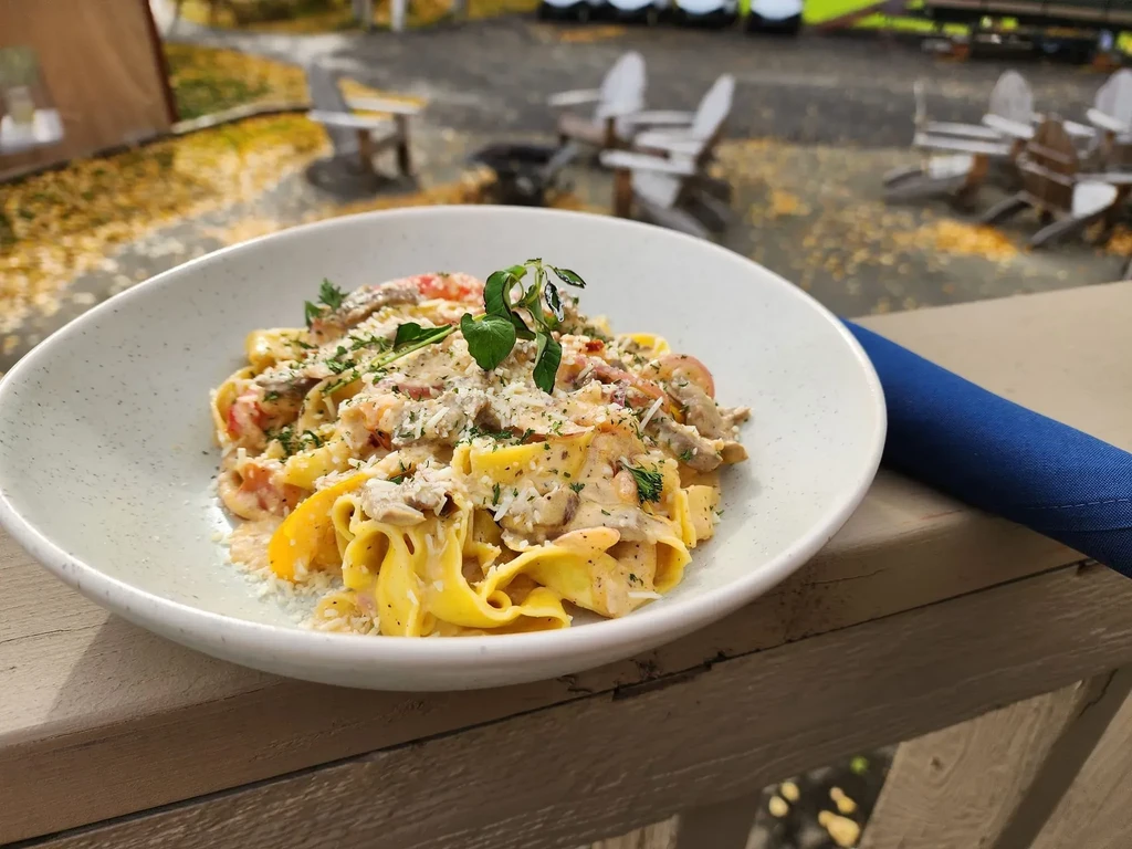 Creamy pasta with mushrooms, cheese, and herbs on an autumn patio.