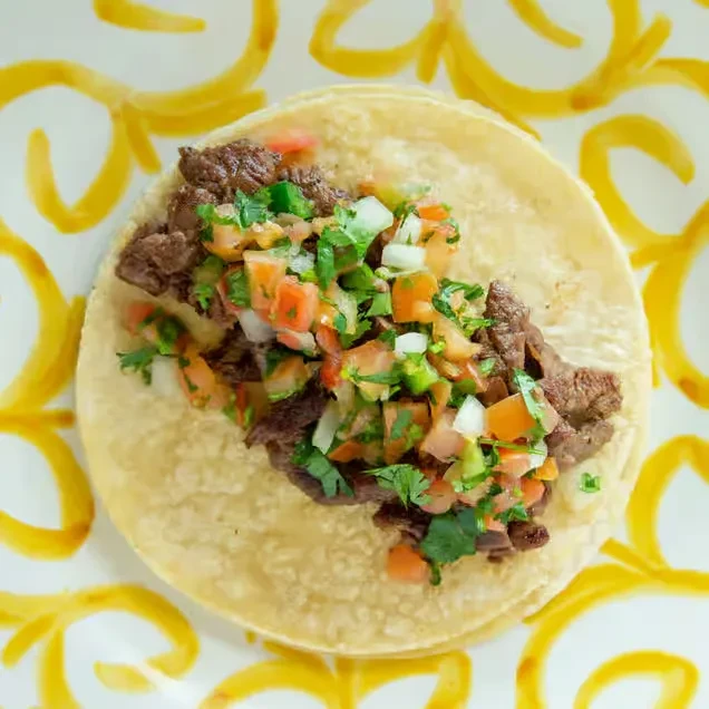 Top-down close-up of a taco with carne asada and pico de gallo.
