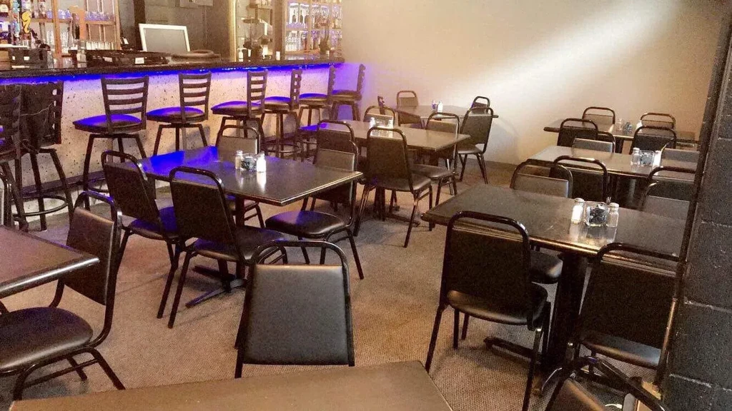 Empty restaurant dining area and bar with vibrant blue LED lighting.