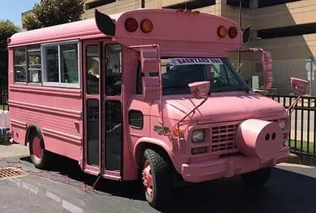 Pink bus with pig ears and snout, 'BARNYARD BUS' banner.