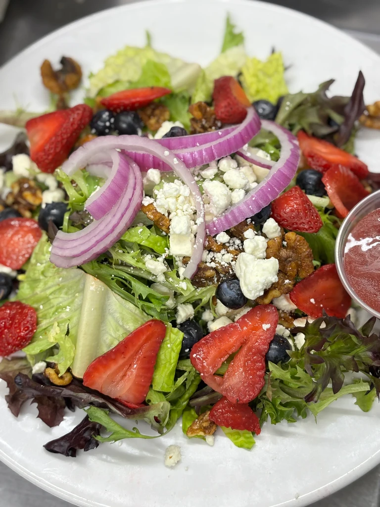 Colorful fresh salad with berries, feta, nuts, and red onion.