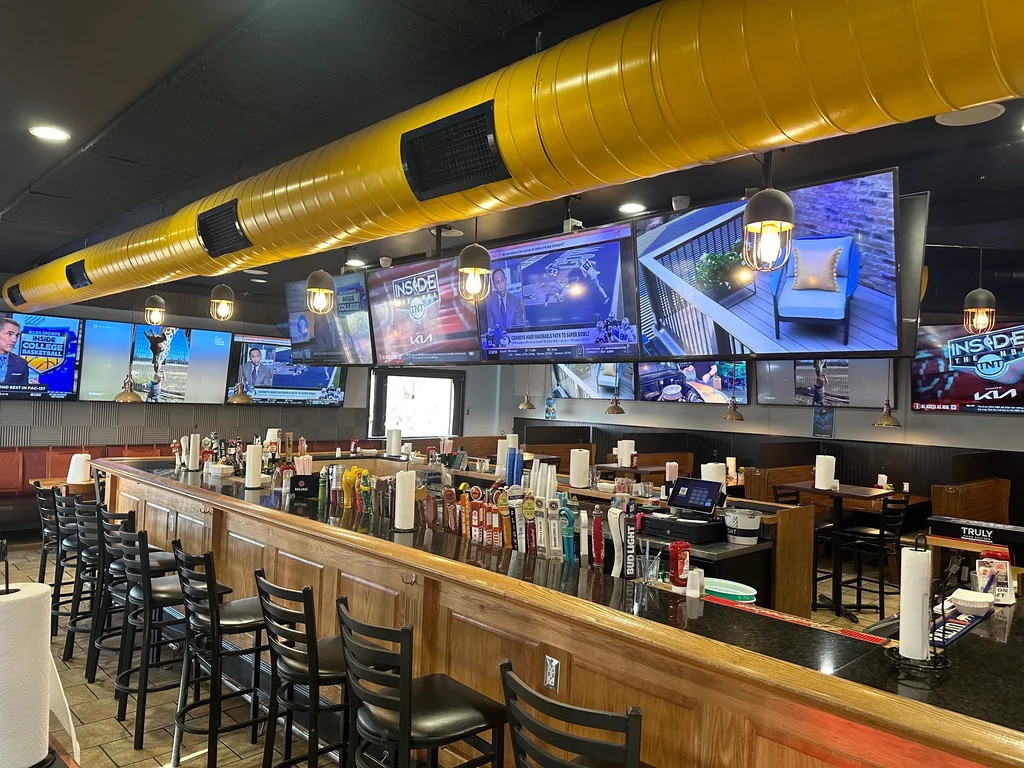 Empty sports bar with long counter, multiple TVs, yellow duct.