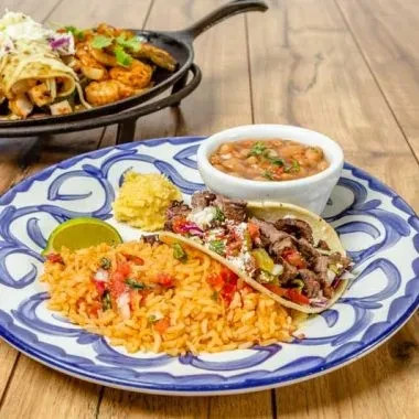 Vibrant Mexican plate with a taco, rice, beans, and fresh lime.