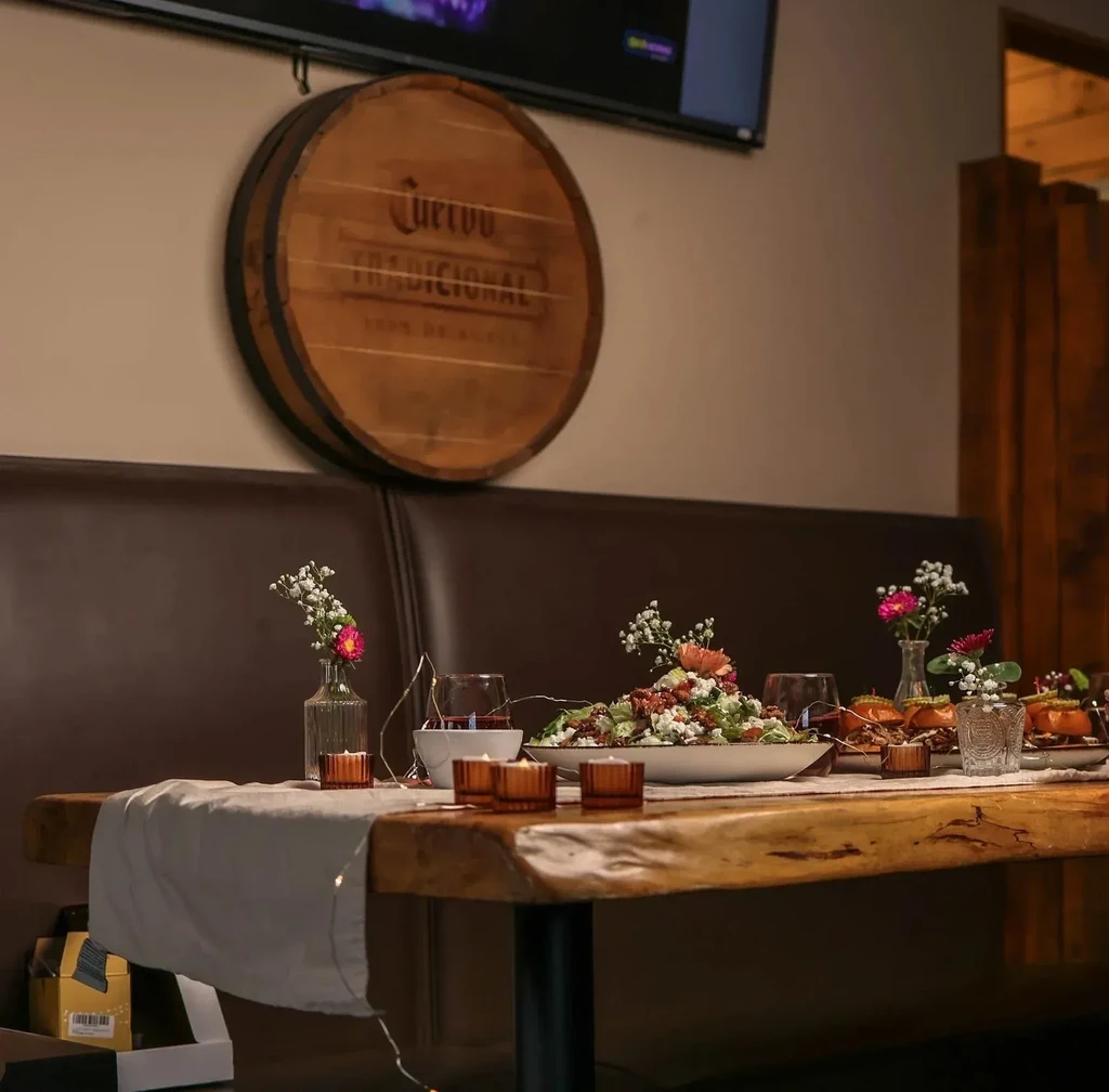 Rustic dining table with salad, wine, flowers, Cuervo barrel.