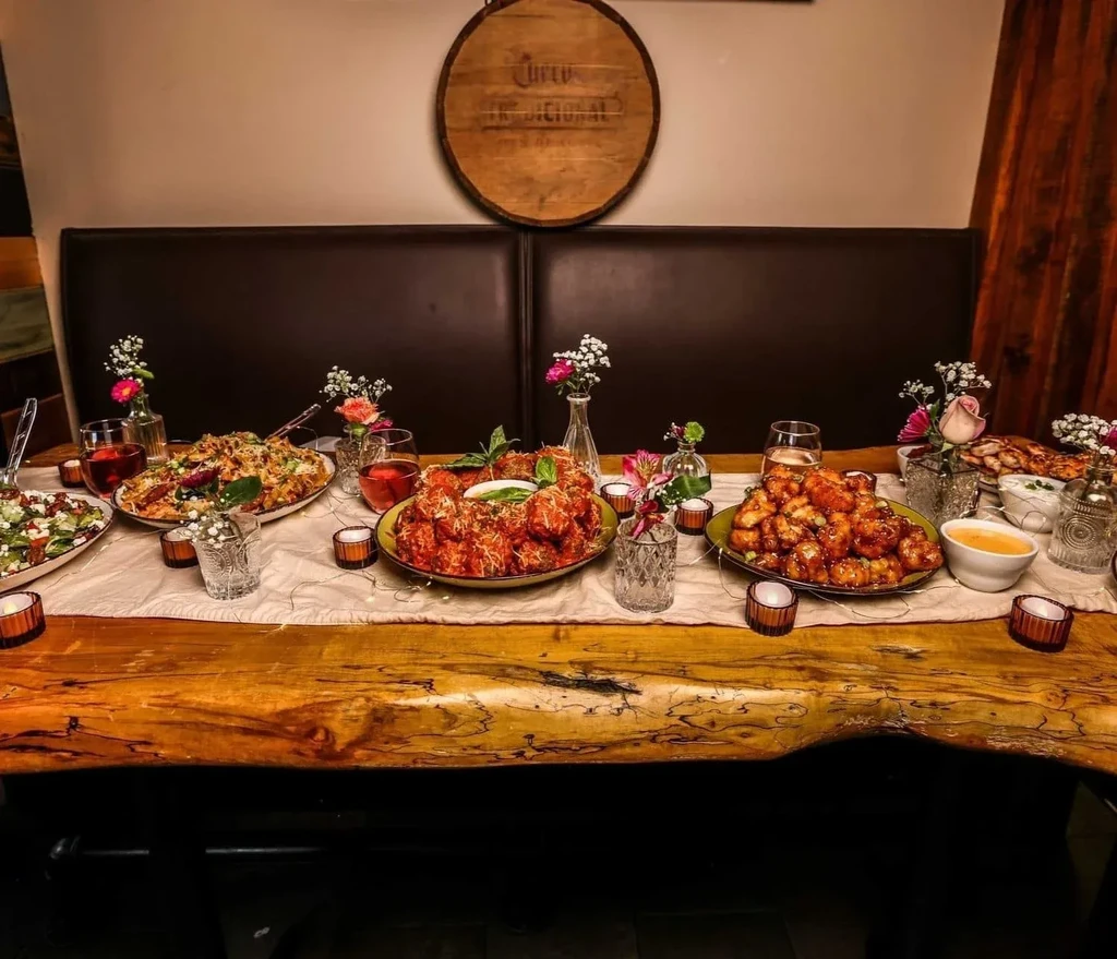 Long wooden restaurant table laden with food, drinks, and decor.