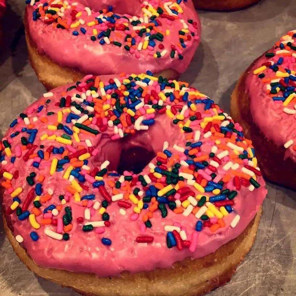 Pink-iced donuts with colorful sprinkles, close-up.