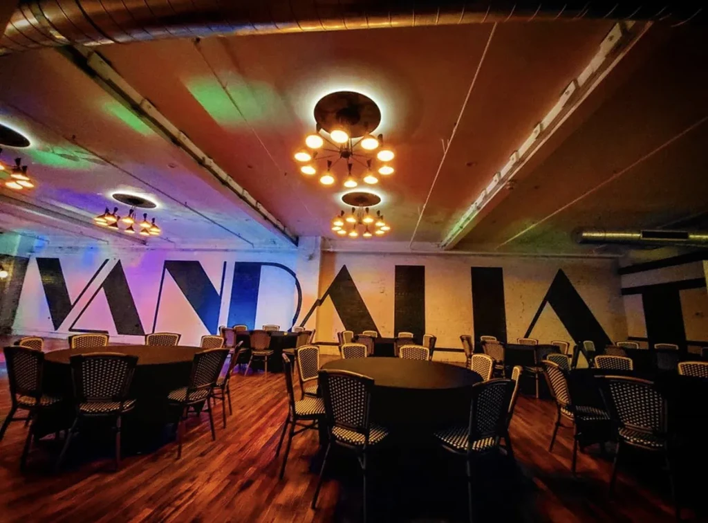 Modern dining room with dark tables, industrial lighting, and a 'VANDALIA' sign.