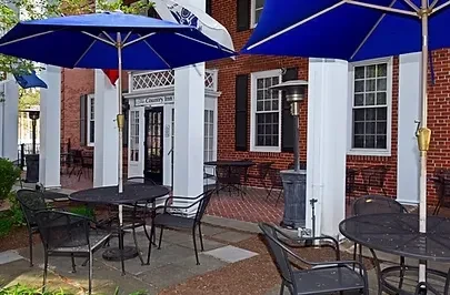 Outdoor patio of The Country Inn with blue umbrellas and seating.