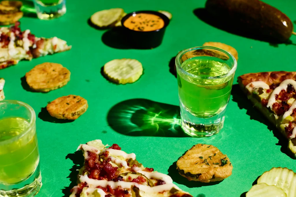Green drinks, fried pickles, and pizza arranged on a bright green table.