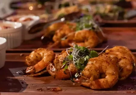 Seasoned shrimp on a wooden board, garnished with microgreens.
