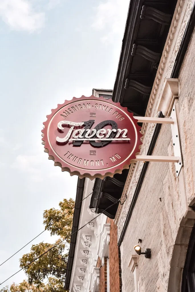 Worm's-eye view of ornate "70 Tavern" bottle cap sign.
