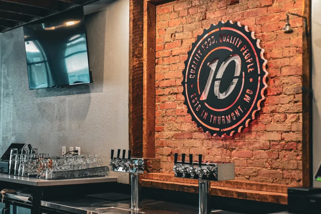 Circular '10' sign on brick wall in modern bar with beer taps.