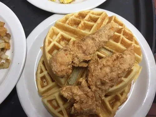 Fried chicken and waffles on a white plate, with hash browns and eggs.