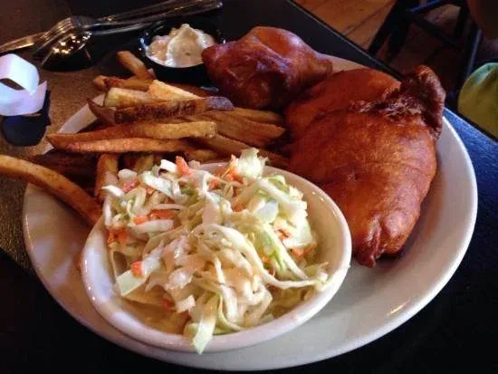A plate of golden fried fish, fries, coleslaw, and tartar sauce.