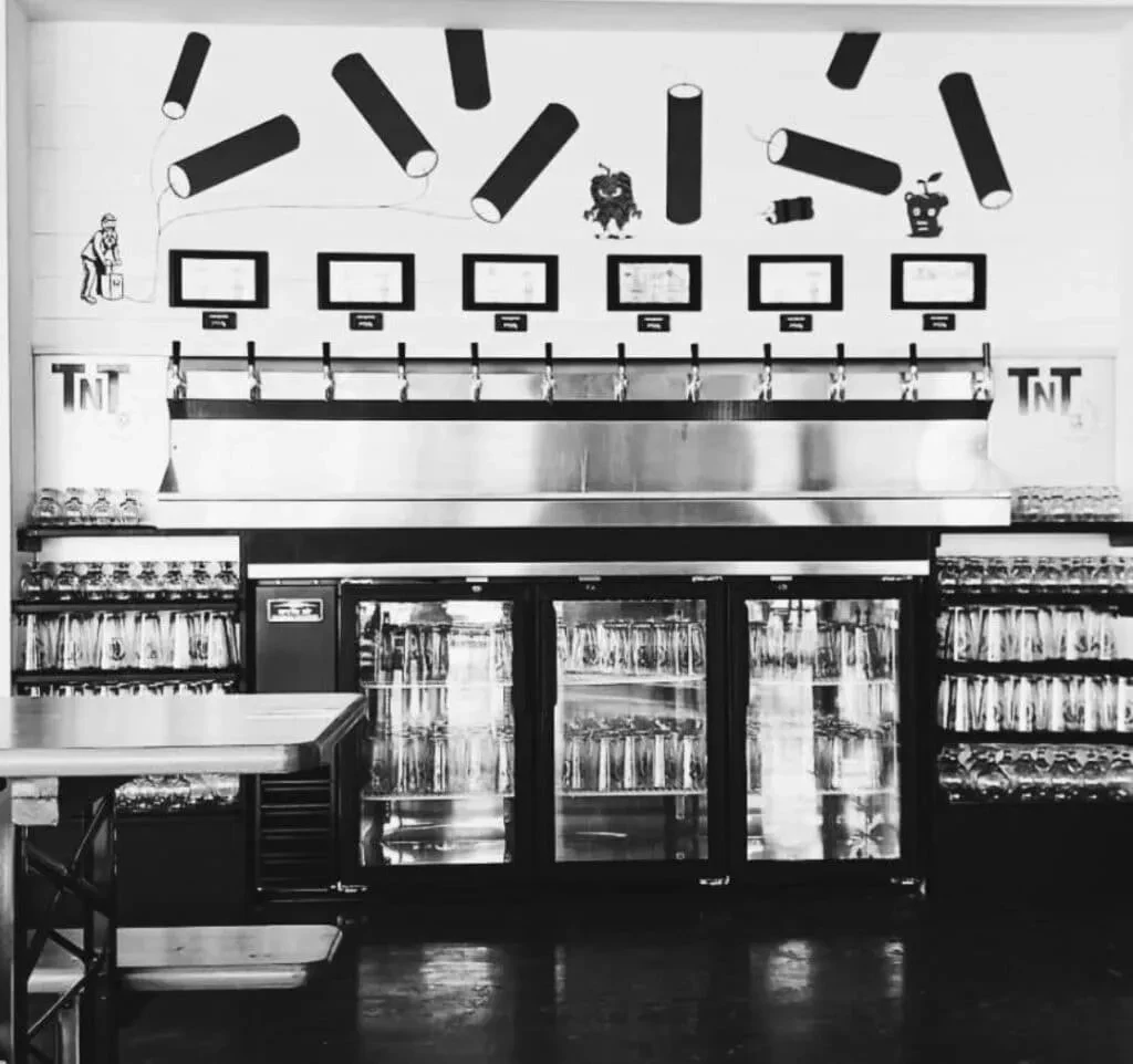 Modern self-serve beer tap wall with cartoon mural, black and white.