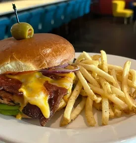 Burger with bacon, melted cheese, red onion, and golden french fries.