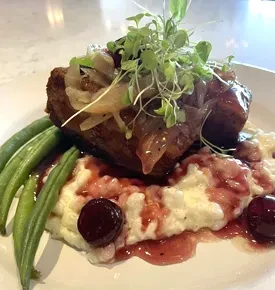 Braised meat with onions, microgreens, creamy potatoes, cherry sauce, green beans.