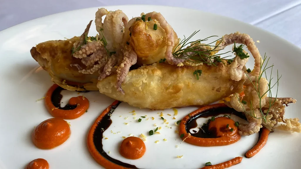 Fried calamari on golden-brown base with herbs and two sauces.