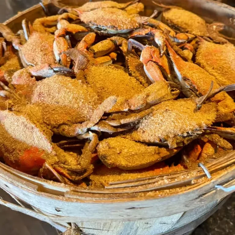 Cooked, seasoned crabs piled high in a rustic wooden bushel basket.