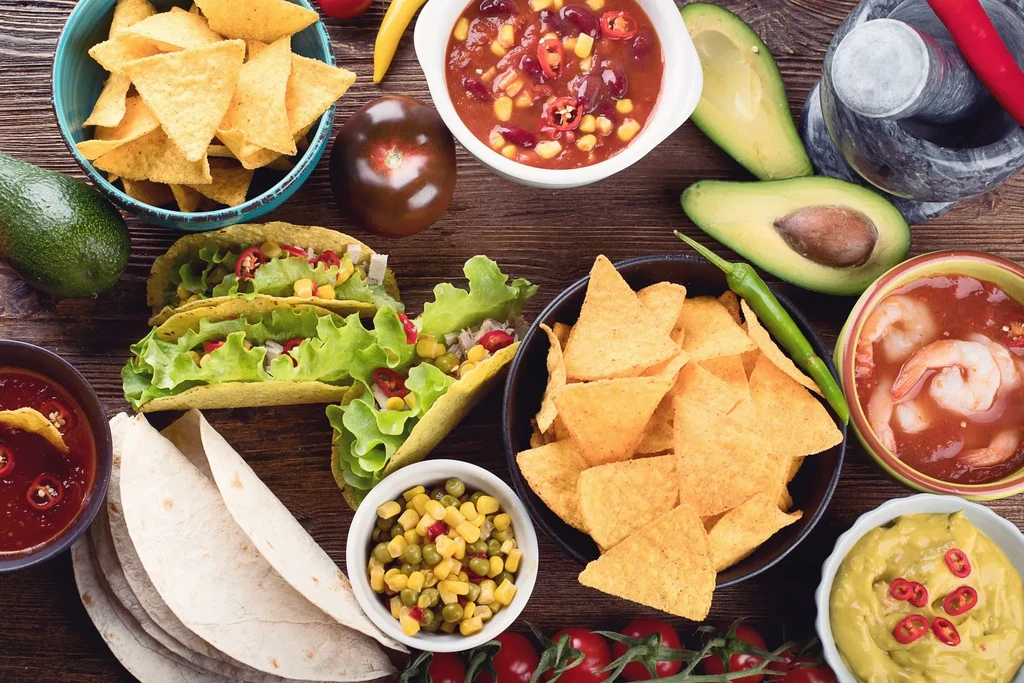Top-down view of tacos, nachos, guacamole, and fresh Mexican food spread.