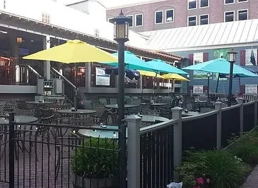 Outdoor restaurant patio featuring fenced and elevated seating with colorful umbrellas.