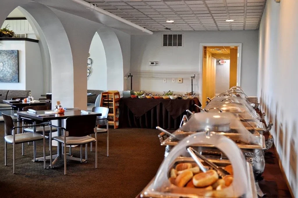 Bright, empty restaurant buffet with hot chafing dishes and cold food.