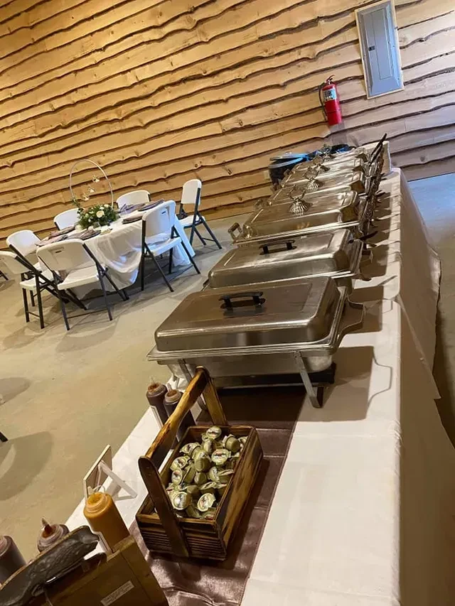 Buffet table with chafing dishes and dining tables in an empty event space.