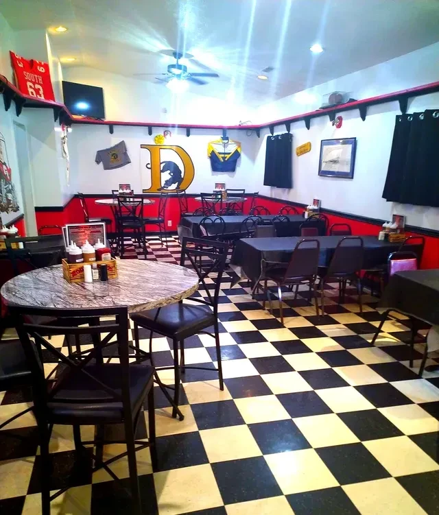 Empty casual restaurant interior: checkerboard floor, red walls, dining tables.