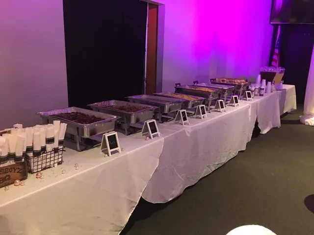 A colorful buffet with chafing dishes, drinks, and Boyz BBQ branding.