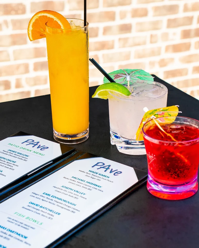 Three vibrant drinks with PAVe Patio Drink Menus on a table.