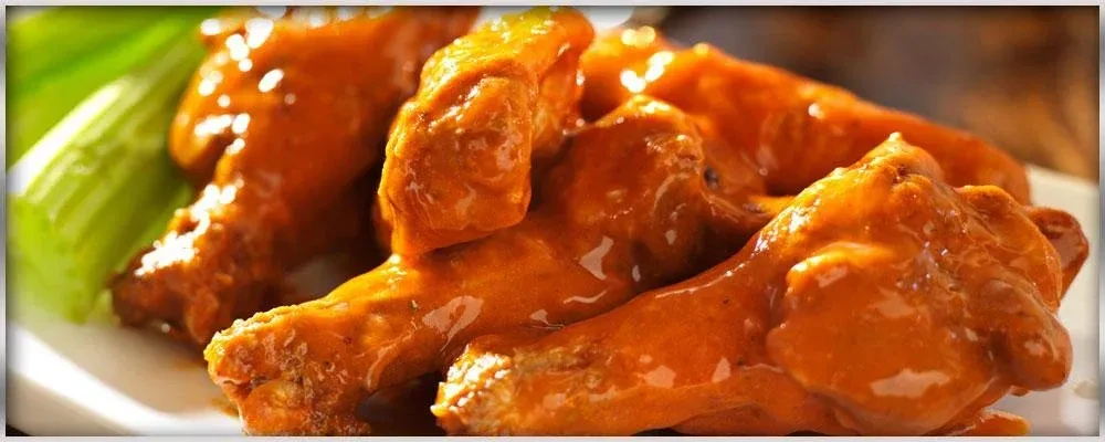 Close-up of glossy buffalo chicken wings and bright green celery.