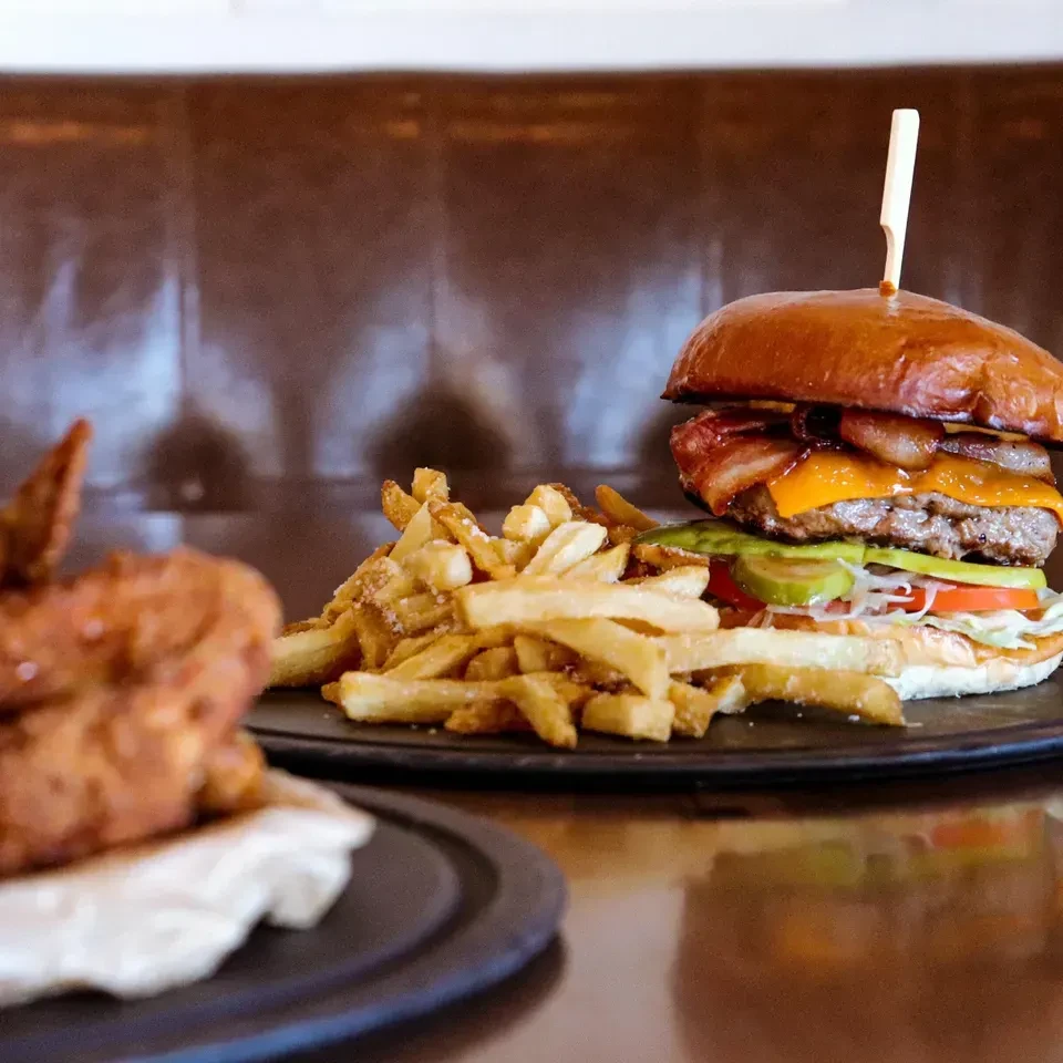 A gourmet burger, fries, and breaded item on dark plates.