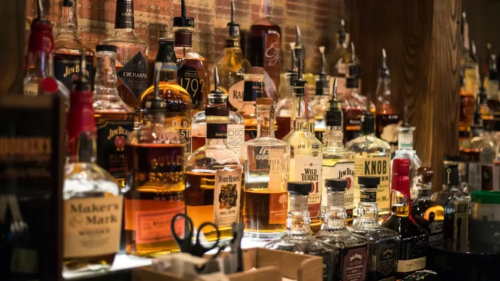 Densely packed liquor shelf with numerous whiskey and bourbon bottles.