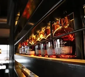 Weller Reserve whiskey bottles on a warm, golden-lit bar shelf.