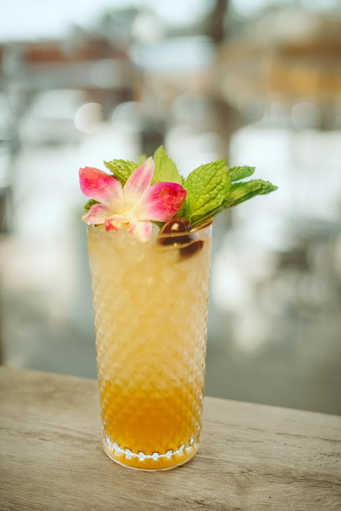 Two-toned cocktail in diamond glass with orchid, mint, and berries.