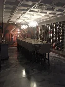 Dim wine room with long table, wine rack, and barrel mural.