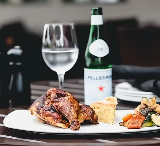 Restaurant meal: roasted chicken, savory tart, vegetables, and San Pellegrino.