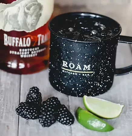 Camping mug with drink, ice, Buffalo Trace bourbon, blackberries, and lime.