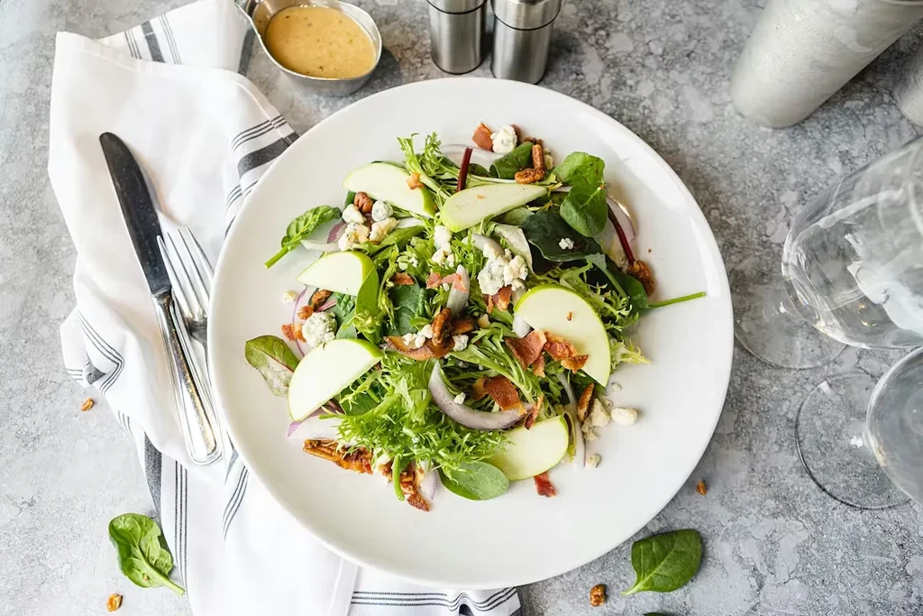 Overhead shot of vibrant salad with apple, blue cheese, bacon, pecans.