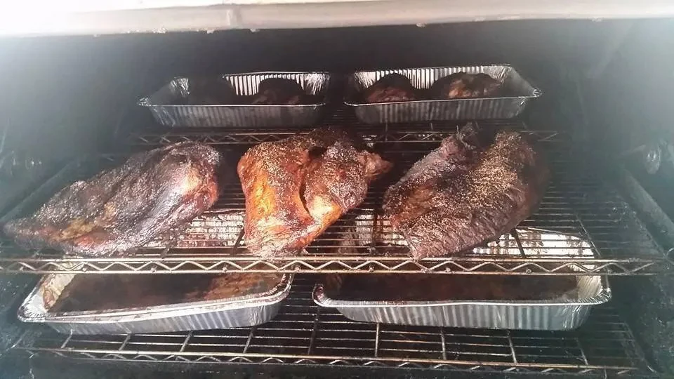 Three large, dark, seasoned meats cooking inside an oven.
