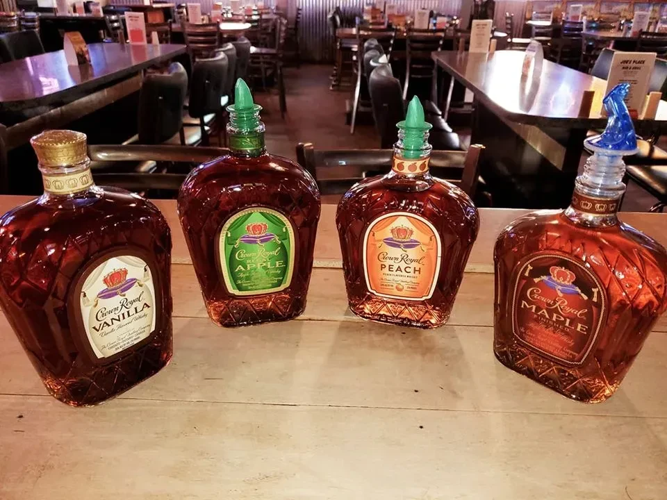 Four Crown Royal flavored whiskey bottles: Vanilla, Apple, Peach, Maple.