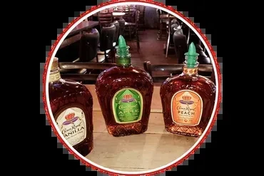 Three Crown Royal bottles: Vanilla, Apple, and Peach, on a bar.