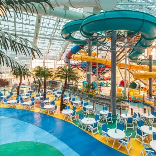 Indoor water park features colorful slides, glass ceiling, dining, and pool.