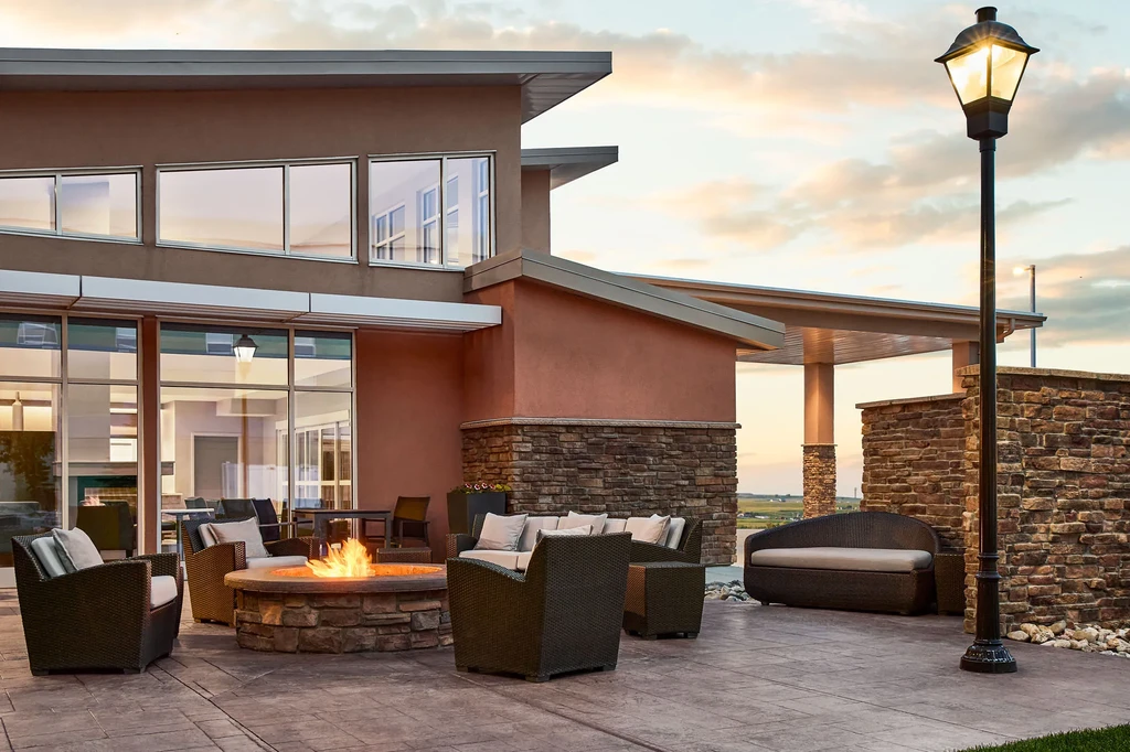 Outdoor patio with fire pit, wicker seating, and modern building.